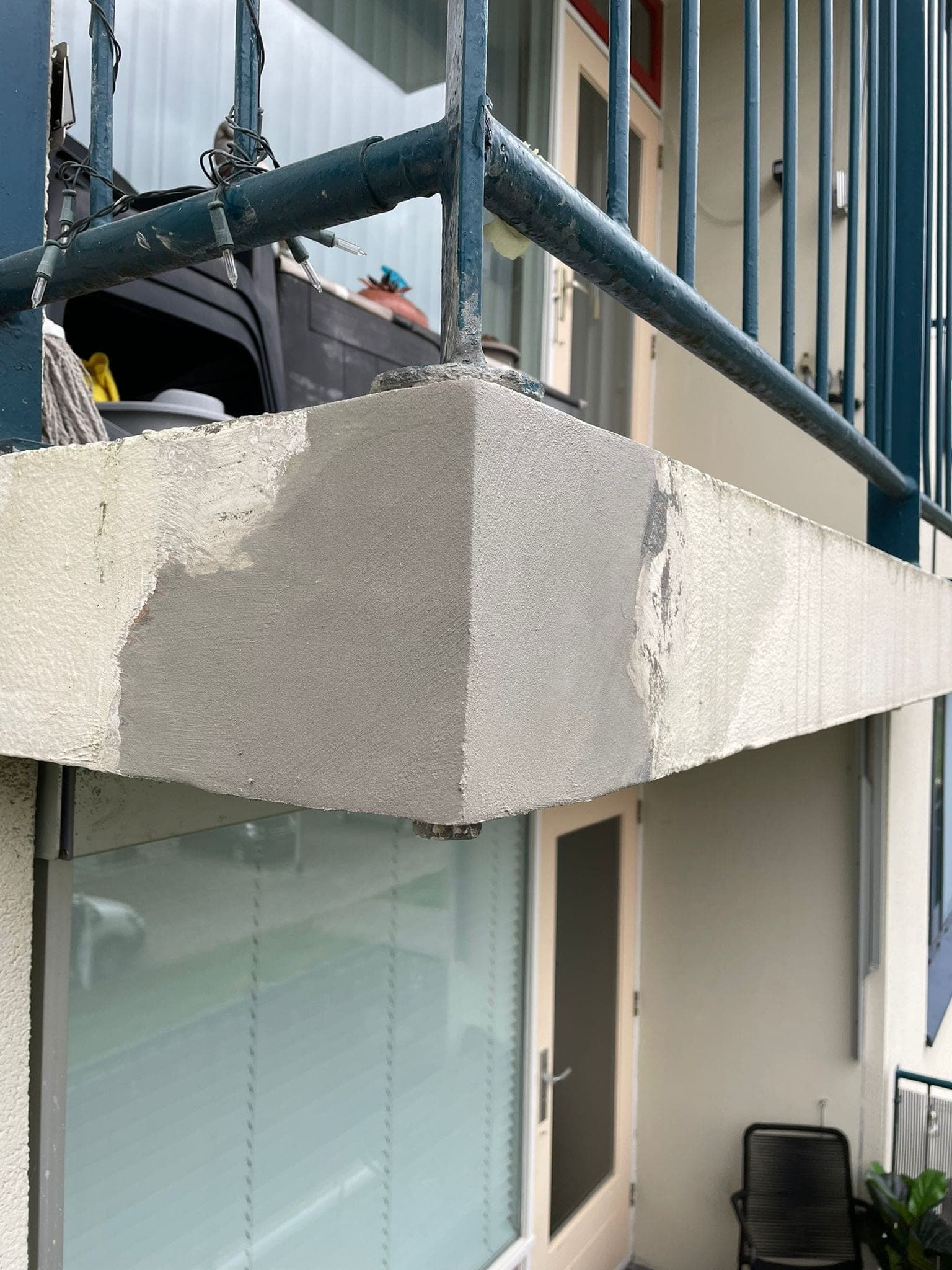 Balkonrand met verse reparatiemortel, gezien vanaf de steiger